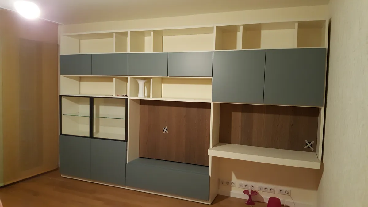Un mur de rangements sur mesure, niches ouvertes et portes grises