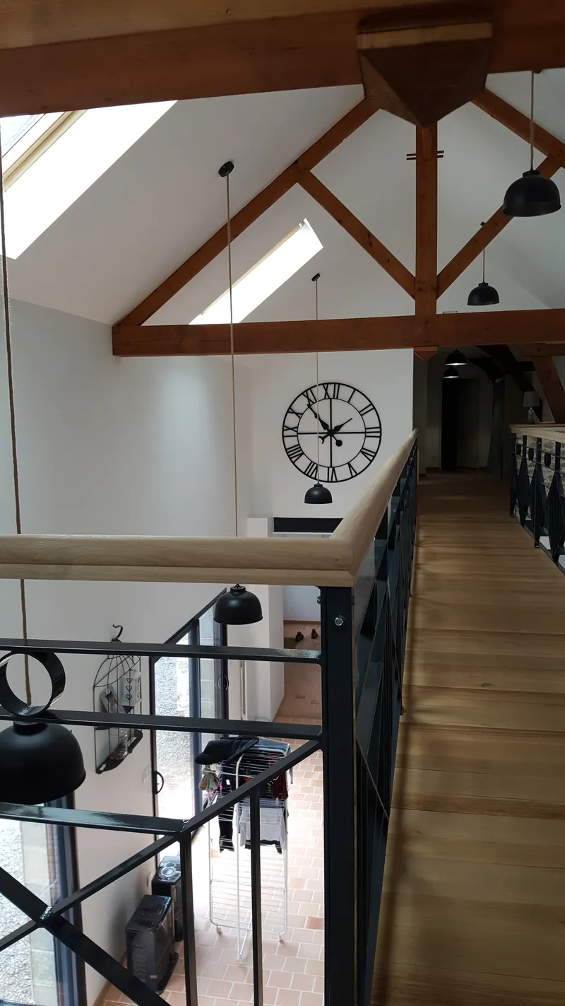 Une mezzanine au plancher de bois, sous une charpente apparente