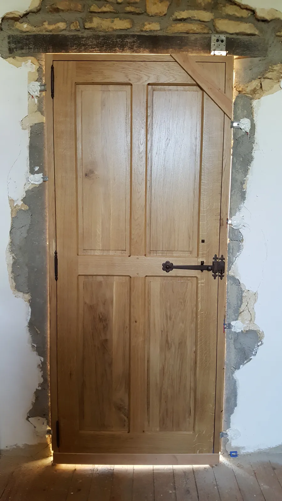 Une porte en bois à panneaux, posée dans un mur de pierre