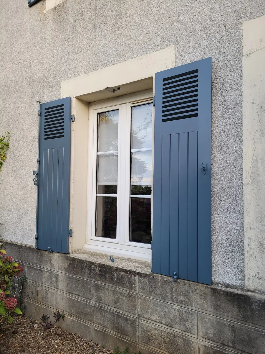 Volets battants bleu ardoise autour d’une fenêtre blanche
