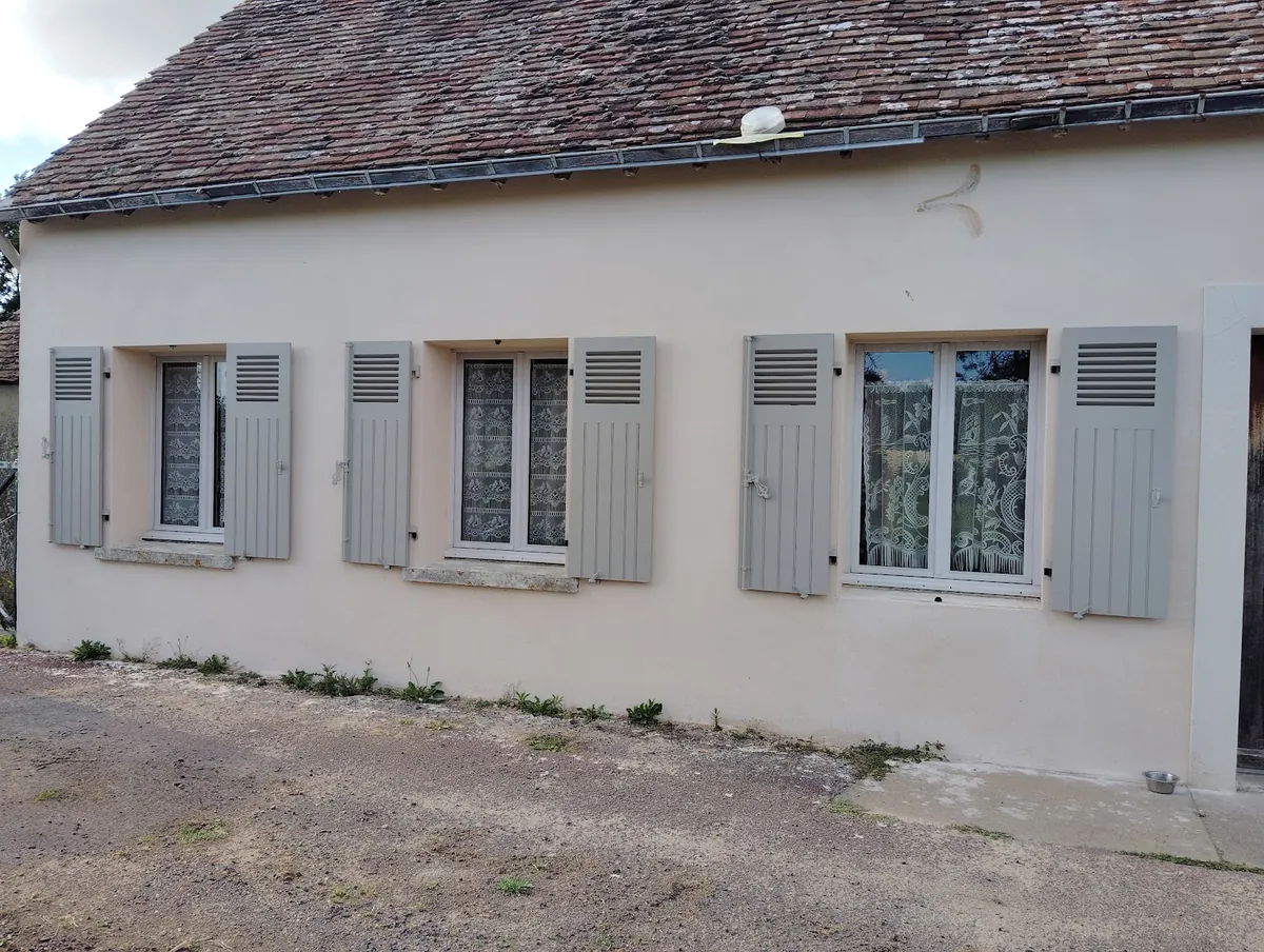 Façade blanche avec trois paires de volets battants gris
